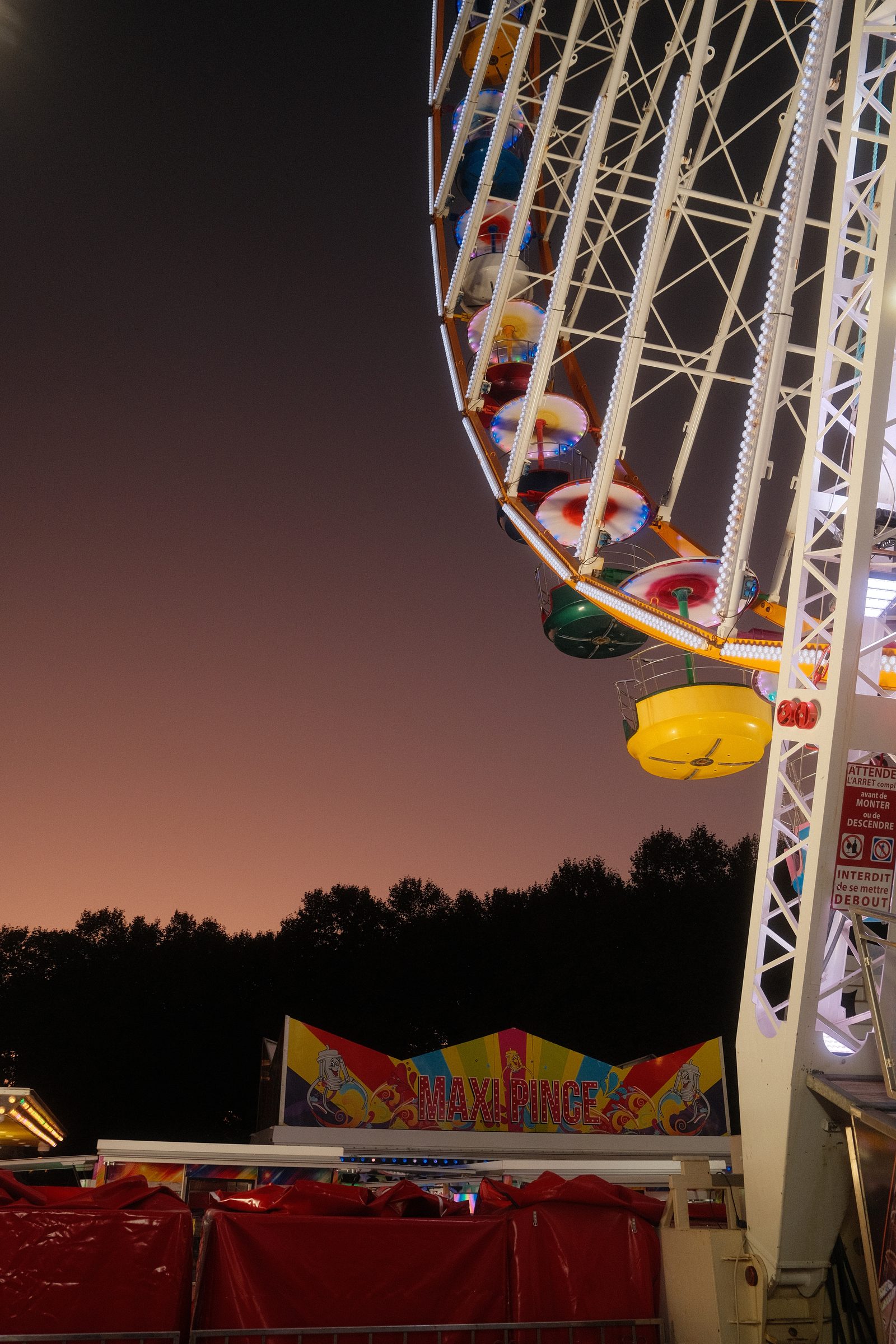 Une portion de grande roue et ses nacelles colorées au crépuscule