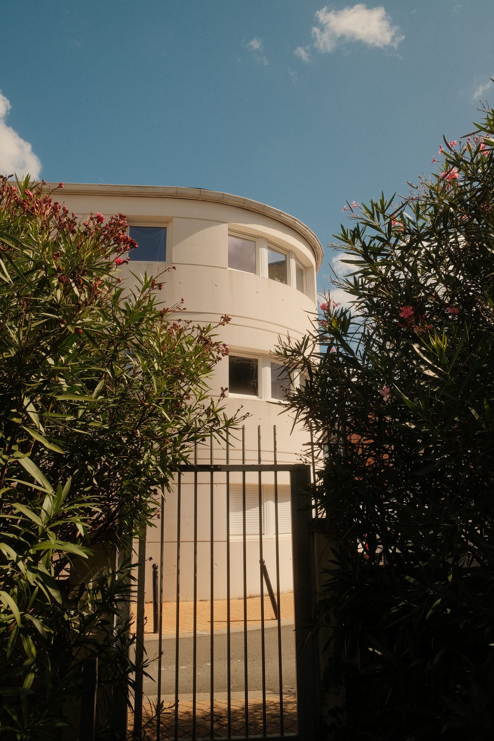 Une maison blanche arrondie entre deux haies