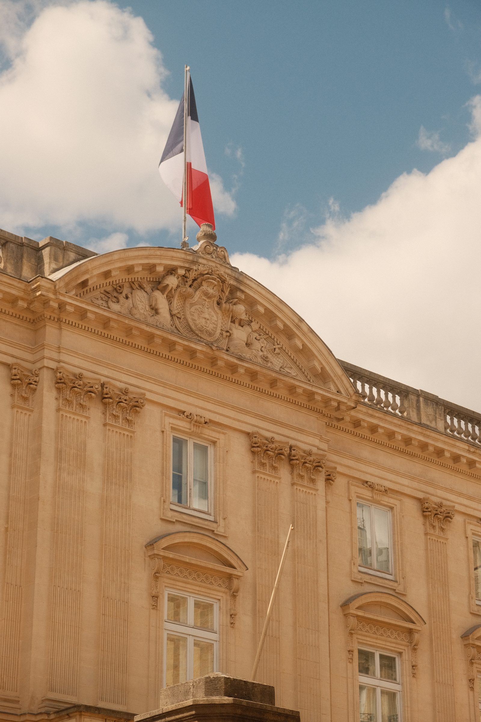 Un fronton de pierre et son drapeau dans le ciel